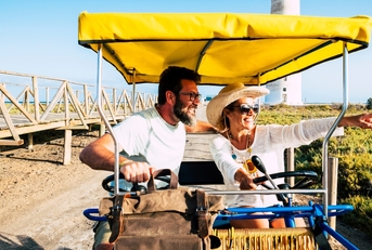 happy adult couple on a surrey bike enjoying the outdoor