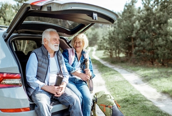 senior couple sitting at the car trunk