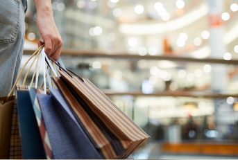 woman standing at mall holding shopping bags in hand
