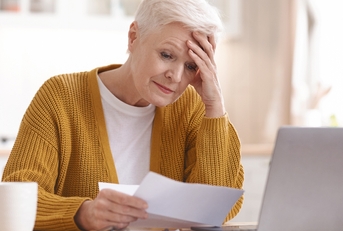 upset senior lady reading bills having financial troubles
