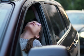 woman sitting in driving seat stuck in traffic looking out of window in frustration