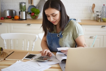 woman sitting on table at home with papers and laptop calculating home budget