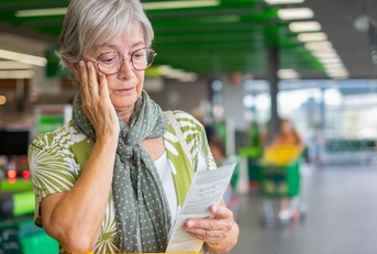 senior woman in the supermarket checks her grocery receipt