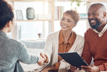 African American couple shaking hands with female financial advisor at home