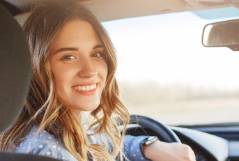 woman sitting in driving seat in car smiling while looking back