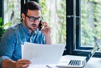 manager reviewing documents while talking on smartphone