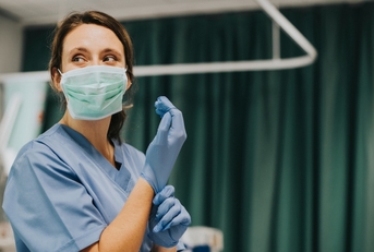 nurse putting on gloves in hospital room