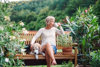 senior woman sitting on bench at terrace enjoying coffee