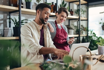 shop assistants with laptop working in potted plant store