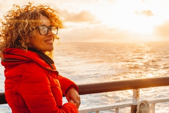 young adult woman enjoying sunset  on a ferry cruise