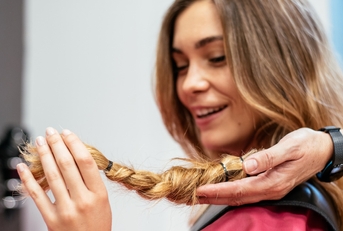 woman at hair salon cutting her hair short to donate it to cancer patients