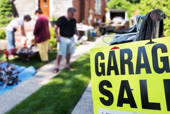 garage sale sign in front of house with shoppers in background
