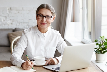 talented mature woman writer sitting in front of laptop
