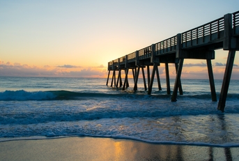 vero beach pier at sunset with water at shore