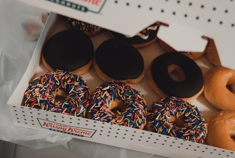 Close up of Krispy Kreme donuts with chocolate glaze and colorful sprinkles.
