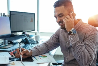 economist analysing statistical data of different parameters and discussing with other colleague at phone call while sitting in office