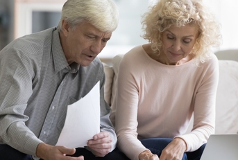 A retired married couple looking at a budget