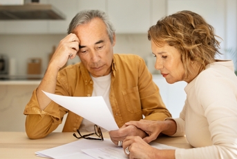 senior spouses sitting at table full of papers
