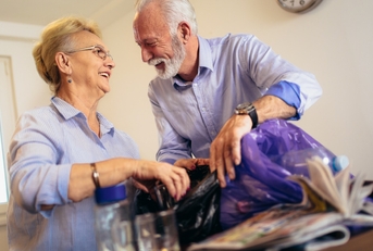 smiling senior couple recycling trash