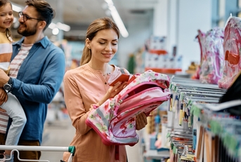 happy mother choosing backpack for daughter