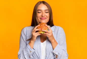 cheerful woman smelling burger