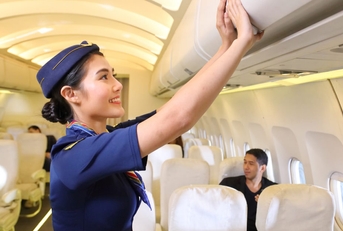 female flight attendant closing luggage compartment