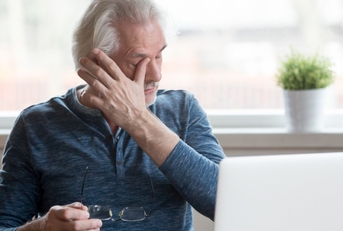 Businessman getting tired while using laptop