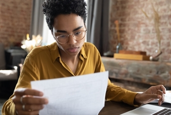 woman in eyeglasses looking through paper