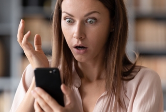 woman shocked at news on smartphone