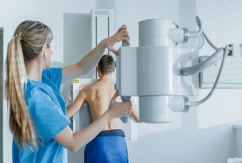 medical technician adjusts x-ray machine
