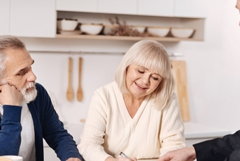 senior couple signing documents with agent