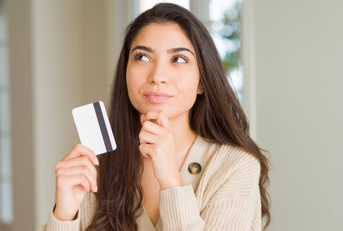 woman holding card while thinking
