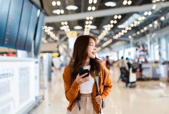 asian woman using mobile at airport