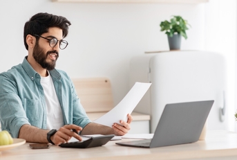 young man calculating taxes using calculator