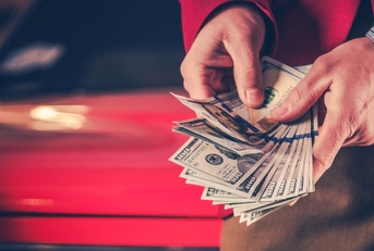 man counting money over vintage car