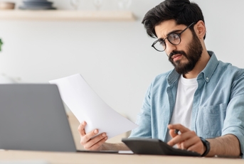 man calculating bills at kitchen table
