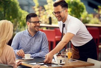 male waiter serving food to couple
