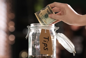 woman putting banknotes into glass jar