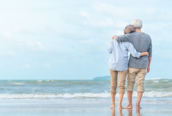 senior couple enjoying beachside waves