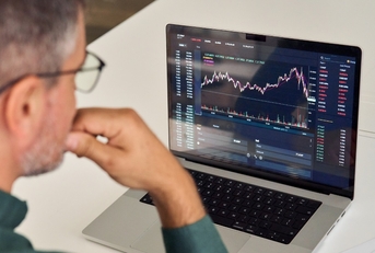 male broker analysing graphs on laptop