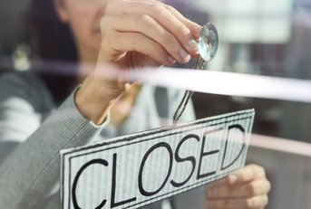 woman hanging closed sign on door