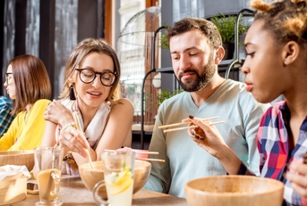 multi ethnic friends eating at restaurant