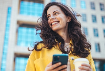 Smiling woman holding a phone and coffee