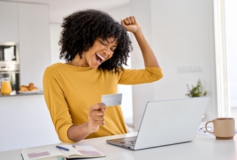 Happy woman holding a credit card and cheering