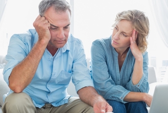 worried senior couple reviewing bills together