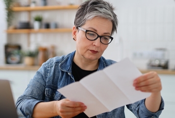 senior woman reading bills in kitchen