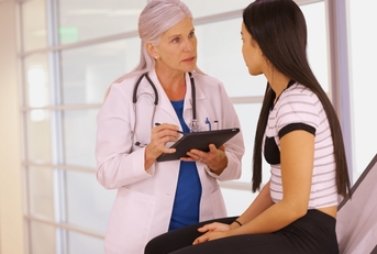 doctor holding tablet checking young girl 