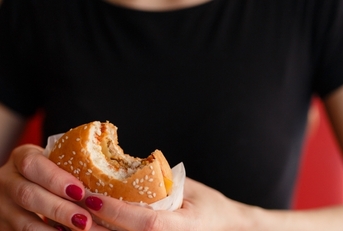 female hands holding fast food burger