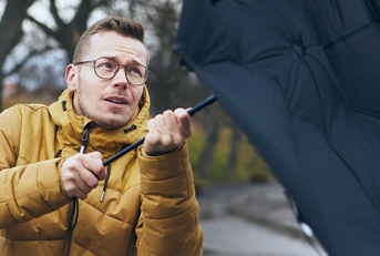 man holding broken umbrella