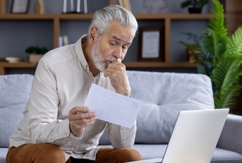 upset senior man reviewing bills